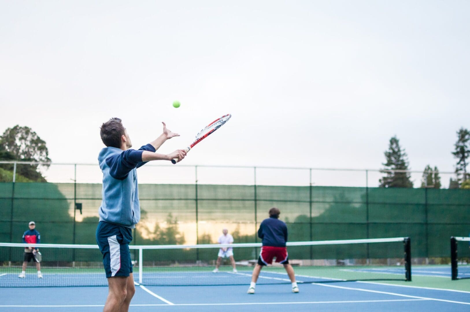 A person playing tennis with other players in the court